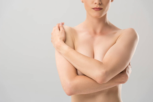 обрезанный вид обнаженной сексуальной женщины, покрывающей грудь, изолированной на серой
 - Фото, изображение