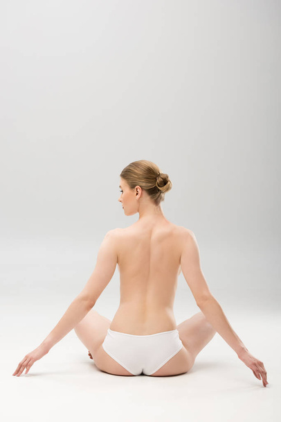 back view of young woman in panties sitting on grey - Photo, Image