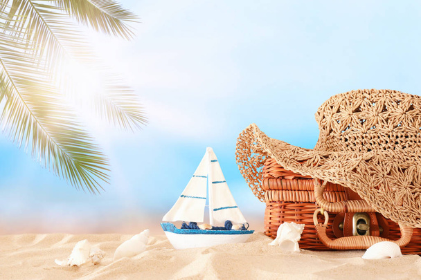 Beach fashion female hat over straw suitcase in the sand. Tropical summer vacation concept - Φωτογραφία, εικόνα