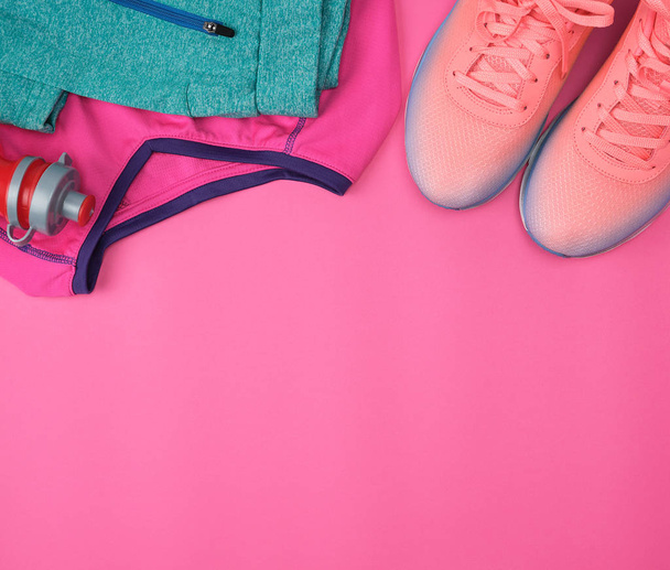 ピンクのバックグルーのボトルに入ったスポーツウェア、靴、淡水 - 写真・画像