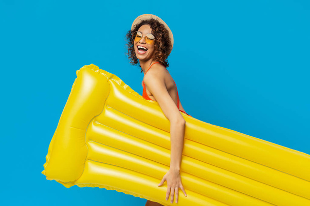 Chica negra alegre que va a la encuesta con el colchón inflable amarillo
 - Foto, imagen