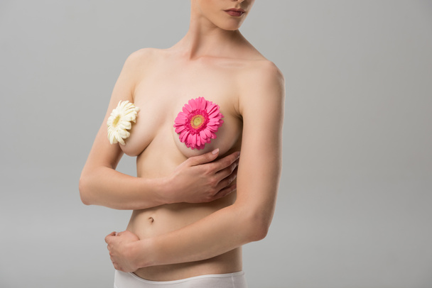 partial view of naked young woman with flowers isolated on grey - Fotografie, Obrázek