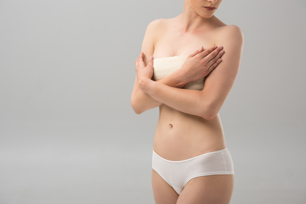partial view of woman in panties with breast bandage isolated on grey - Photo, Image