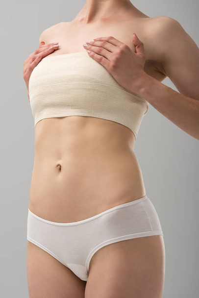 cropped view of woman in panties with breast bandage isolated on grey - Photo, Image