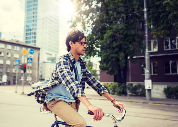 young hipster man with bag riding fixed gear bike - 写真・画像