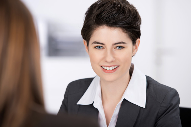 Smiling Businesswoman With Coworker In Foreground - Foto, afbeelding