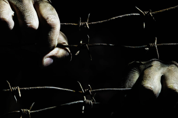 Kirli erkek elleri karanlıkta gerilmiş paslı dikenli tel tutun - Fotoğraf, Görsel