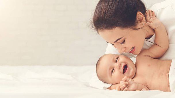 Csiklandozás a baba játék az ágyban otthon anya - Fotó, kép