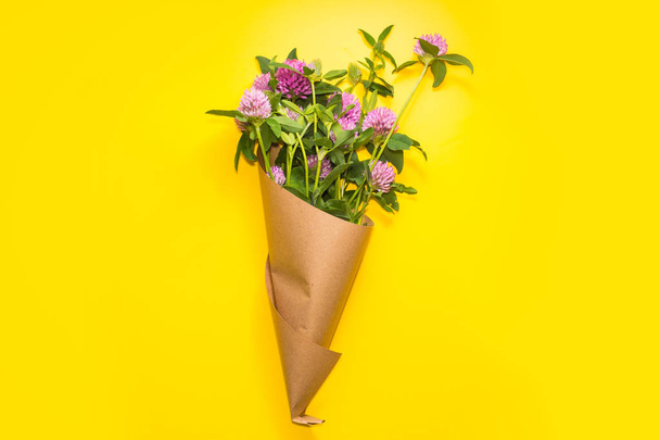 bouquet di trifoglio in un cono di carta su sfondo giallo
 - Foto, immagini