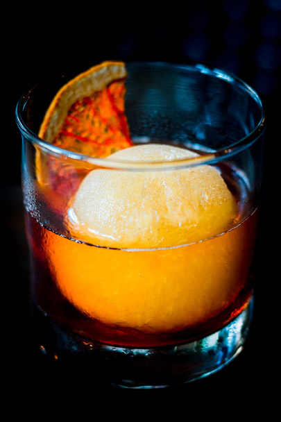 A healthy measure of rum over a big ice ball made of apple juice in a short glass - Foto, immagini