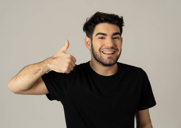 Portrait of good looking young man showing thumbs up sign feeling cheerful, happy and satisfied. Young happy student male making thumb up in joyful approval gesture isolated on white background. - Foto, Imagen