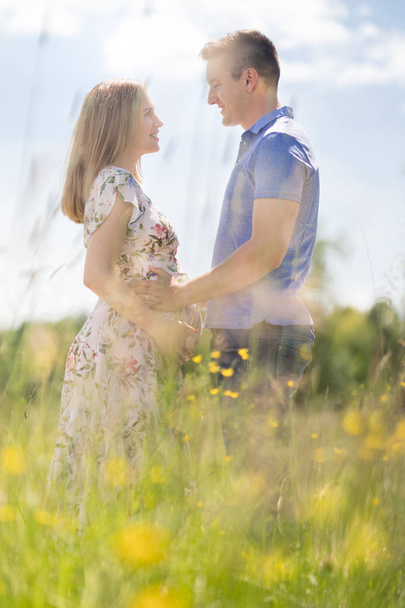 Young happy pregnant couple hugging in nature. - Photo, Image