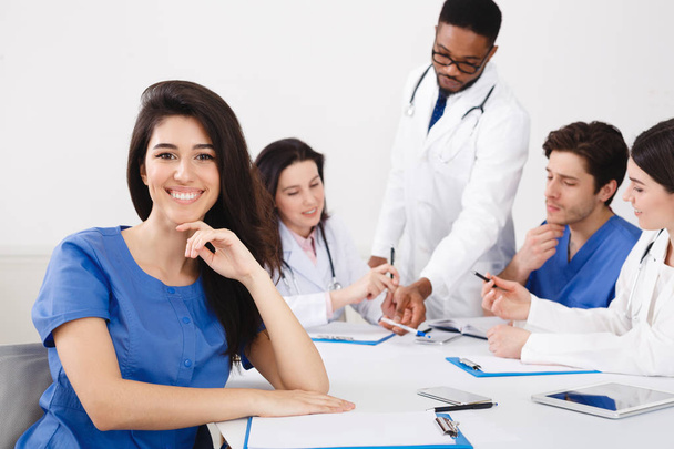 Tıbbi Profesyoneller in Hemşire toplantısı toplantıda kameraya gülümseyerek - Fotoğraf, Görsel