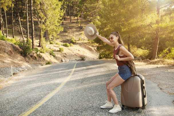 Ωτοστόπ έννοια του τουρισμού. Ταξίδια hitchhiker γυναίκα που περπατά στο δρόμο κατά τη διάρκεια διακοπών ταξίδια - Φωτογραφία, εικόνα
