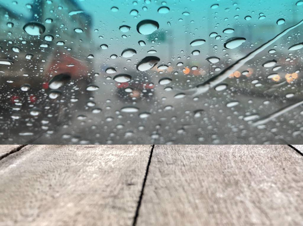 wooden boards in front of car windshield with raindrops on blurred street background with traffic in city at rainy day - Photo, image