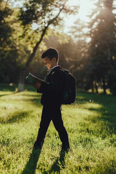 beautiful schoolboy portrait reads the book, is happy after school, profile view, outdoor, at sunset ,  - Valokuva, kuva