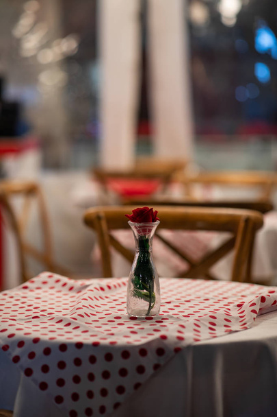 Primer plano de la pieza central de una mesa de restaurante español con mantel a cuadros rojo y sillas de madera
 - Foto, Imagen