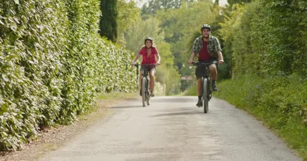 Romántica pareja activa montar en bicicleta eléctrica bicicletas mtb en un hermoso bosque al aire libre sendero senderismo.Amplio shot.Friends viaje italiano en Umbria.4k cámara lenta
 - Metraje, vídeo