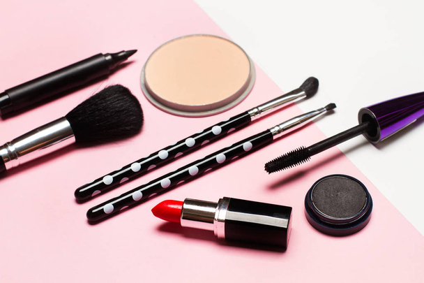 Los rubores, los pinceles y el lápiz labial para el maquillaje sobre el fondo rosado
 - Foto, Imagen