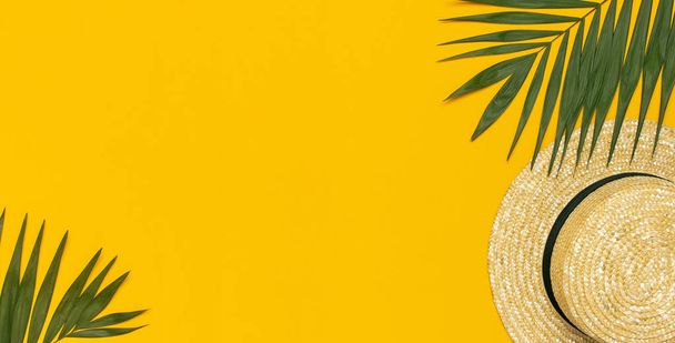 Women s summer straw hat, tropical palm leaves, monstera leaf on yellow background top view flat lay copy space. Summer travel vacation concept. Female accessory, summer background - Photo, Image