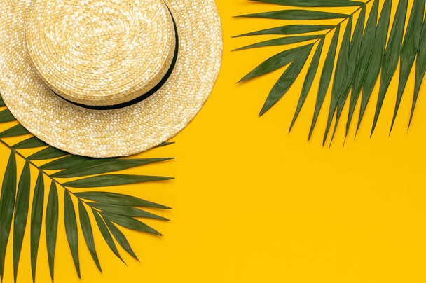 Vrouwen s zomer strooien hoed, tropische palmbladeren, Monstera Leaf op gele achtergrond bovenaanzicht platte lay kopie ruimte. Zomerreis vakantieconcept. Vrouwelijk accessoire, zomer achtergrond - Foto, afbeelding
