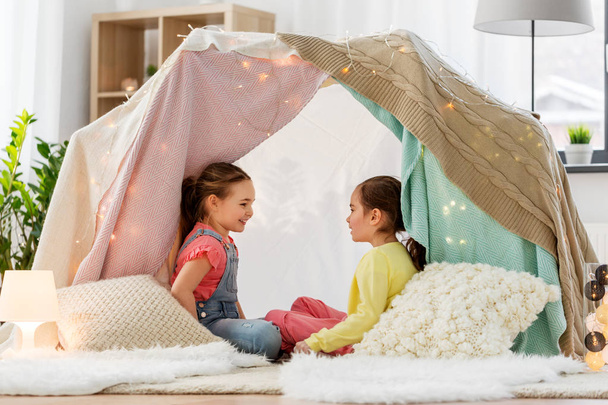 happy girls lying in kids tent and talking at home - Fotó, kép