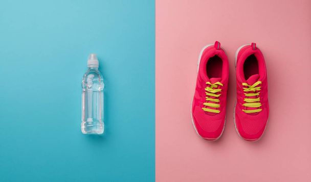 Studio shot of running shoes and water bottle on color background. Flat lay. - Foto, imagen