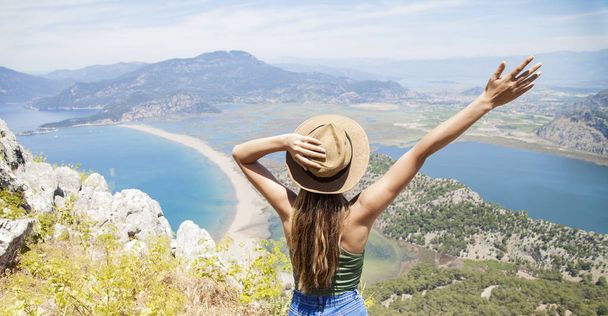 Happy woman with hands up standing on cliff over sea and islands at summer. Vintage mood, concepts of winner, freedom, happiness etc. - Photo, Image