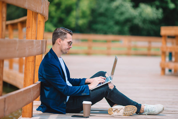 Jeune homme avec ordinateur portable travaillant à l'extérieur dans le parc
 - Photo, image