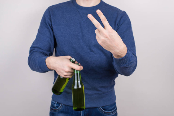 Przycięte zbliżenie zdjęcie przystojny zadowolony pozytywny facet podejmowania symbol v-znak do aparatu gospodarstwa dwa świeże piwa w dłoni na białym tle szare - Zdjęcie, obraz