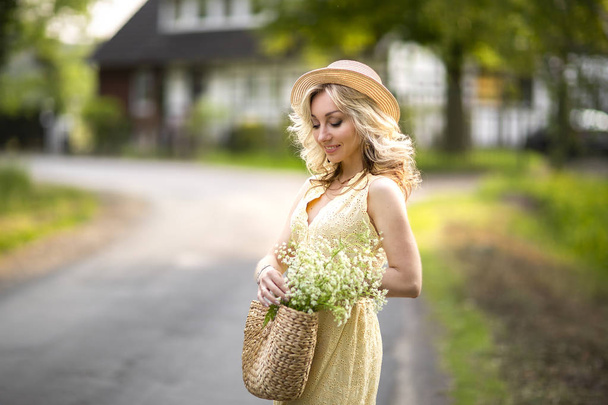 Retrato femenino al aire libre. una mujer en un sombrero de paja en un campo de flores con un ramo de flores silvestres. Verano en el campo
 - Foto, imagen