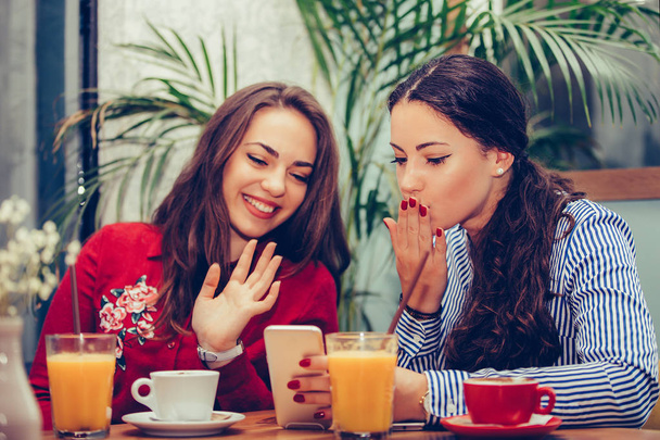 zwei junge Frauen telefonieren mit Freunden auf einem Smartphone. - Foto, Bild