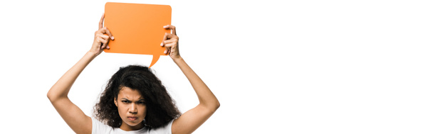 panoramic shot of angry african american girl holding orange speech bubble isolated on white  - Photo, Image