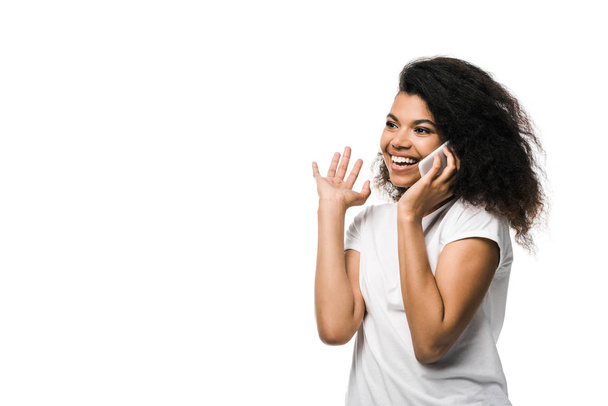 happy african american girl talking on smartphone and gesturing isolated on white  - Foto, Imagem
