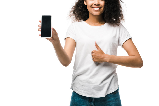 cropped view of happy american girl holding smartphone with blank screen and showing thumb up isolated on white  - Photo, Image