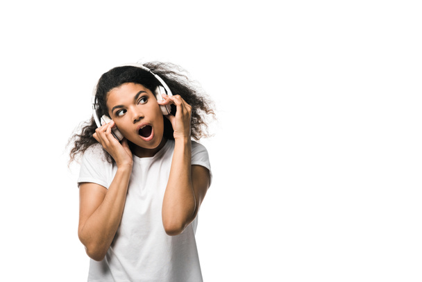 surpreso menina americana africana em fones de ouvido ouvir música isolada no branco
  - Foto, Imagem