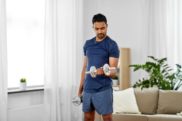 indian man exercising with dumbbells at home - Foto, afbeelding