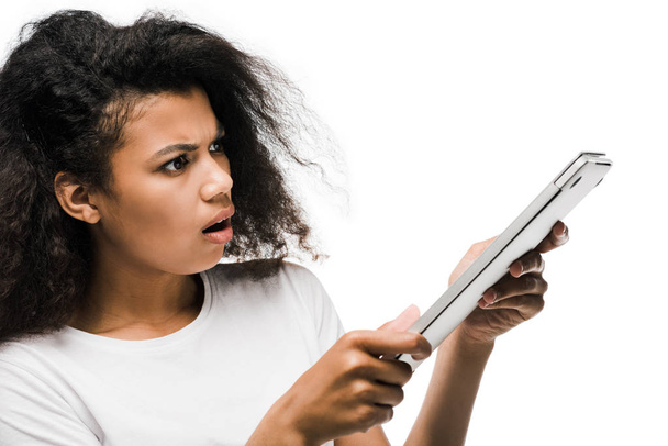 έκπληκτος νεαρή αφρικανική Αμερικάνικη γυναίκα κοιτάζοντας το laptop απομονώνεται σε λευκό  - Φωτογραφία, εικόνα