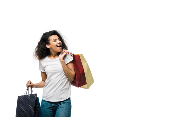 cheerful young curly african american woman holding shopping bags isolated on white  - Фото, зображення