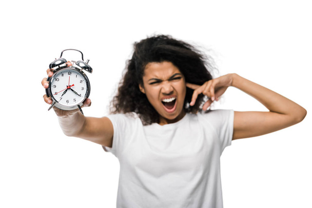 selective focus of vintage alarm clock in hand of displeased curly african american girl isolated on white  - Photo, Image