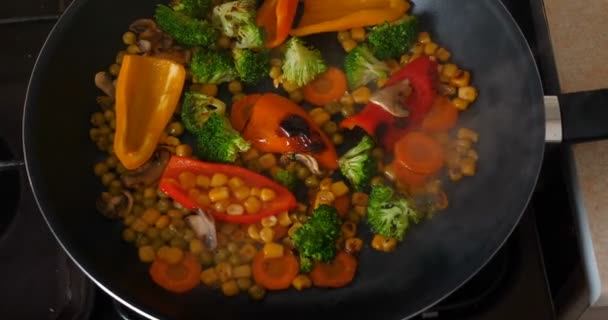 Delicious fresh vegetables are stewed in a pan, food for vegetarians at home. Concept of: Veg, Bio Product, Mushrooms, Broccoli, Colored Cabbage, Carrot, Corn, Paprika. - Кадри, відео