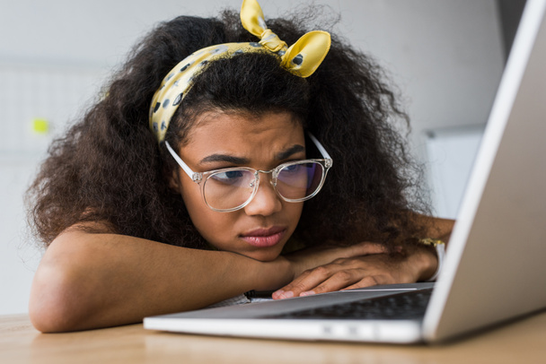 selective focus of upset african american woman in glasses using laptop  - Fotografie, Obrázek