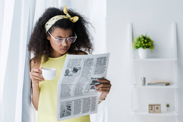 morena afroamericana americana mujer leyendo periódico y sosteniendo taza
  - Foto, imagen