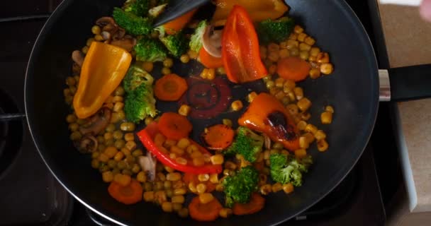 Delicious fresh vegetables are stewed in a pan, food for vegetarians at home. Concept of: Veg, Bio Product, Mushrooms, Broccoli, Colored Cabbage, Carrot, Corn, Paprika. - Metraje, vídeo