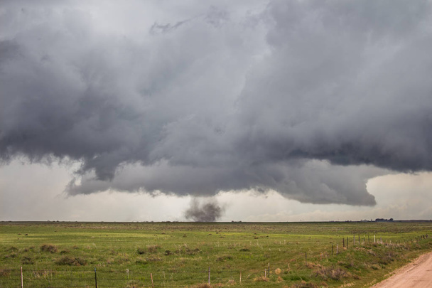 Een Tornado zonder zichtbare trechter raakt op de vlaktes en dwarrelt stof onder een storm. - Foto, afbeelding