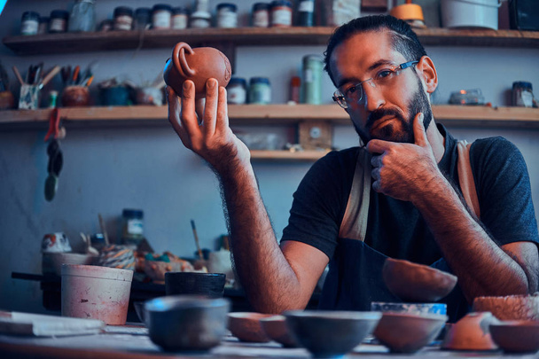 Skeptik se dívá na svou práci, keramický čajník. - Fotografie, Obrázek