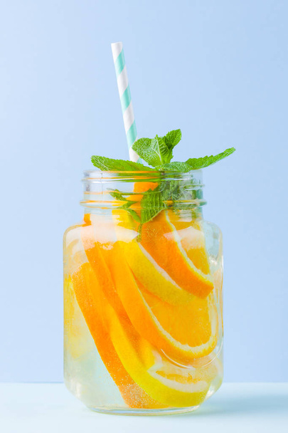 Infused water with fruits on blue background. Mug delicious refreshing drink of mix fruits with mint on blue background. Iced summer drink in mason jar. Minimalism - Photo, Image