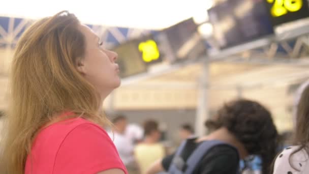 concept van toerisme, vakantie en uitwisseling opleiding. Een vrouw en twee tieners, een jongen en een meisje, staan op de luchthaven op het ticketkantoor voor flight check-in. - Video