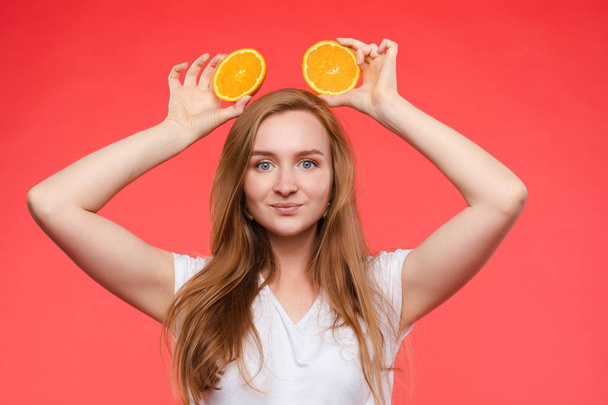 Αστείο μοντέρνο κορίτσι με το χτένισμα κρατώντας πορτοκάλια στα μάτια. - Φωτογραφία, εικόνα