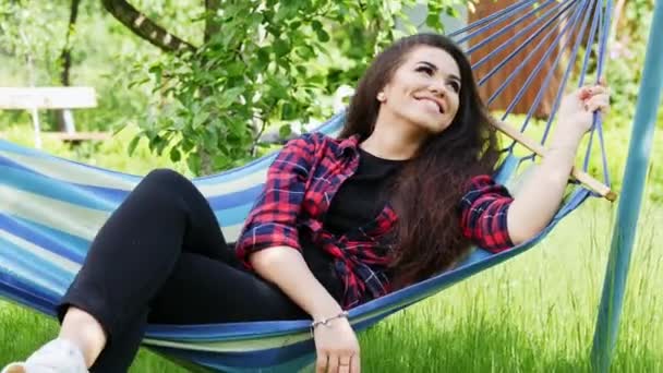 Krásná mladá žena užívající dovolenou v houpací síti, šťastná dívka se usmívá - Záběry, video